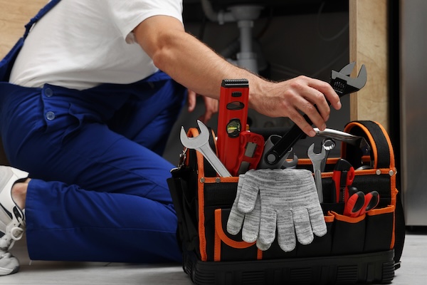 Professional Plumber Taking Adjustable Wrench From Tool Bag Indoors Closeup